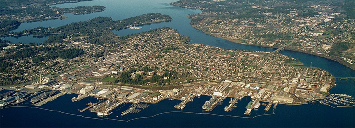 Puget Sound Naval Shipyard & Intermediate Maintenance Facility and Bremerton, Washington, as viewed from the air above Sinclair Inlet. The Washington State Ferries Bremerton terminal can be seen at the lower right corner of the photo.